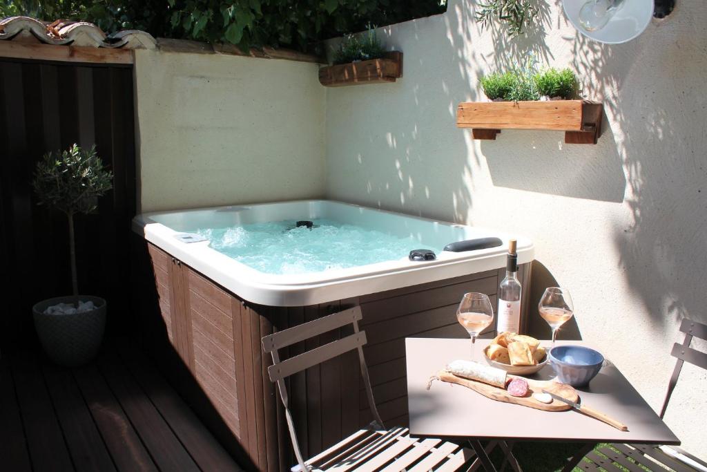 - un bain à remous sur une terrasse avec une table et des verres à vin dans l'établissement LA PETITE MAISON DE MAUSSANE ***, à Maussane-les-Alpilles