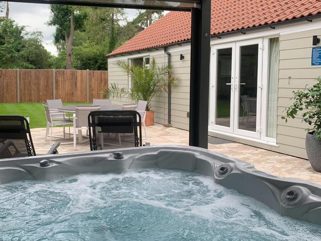 a hot tub in a backyard with a table and chairs at Little Orchard in Worlington