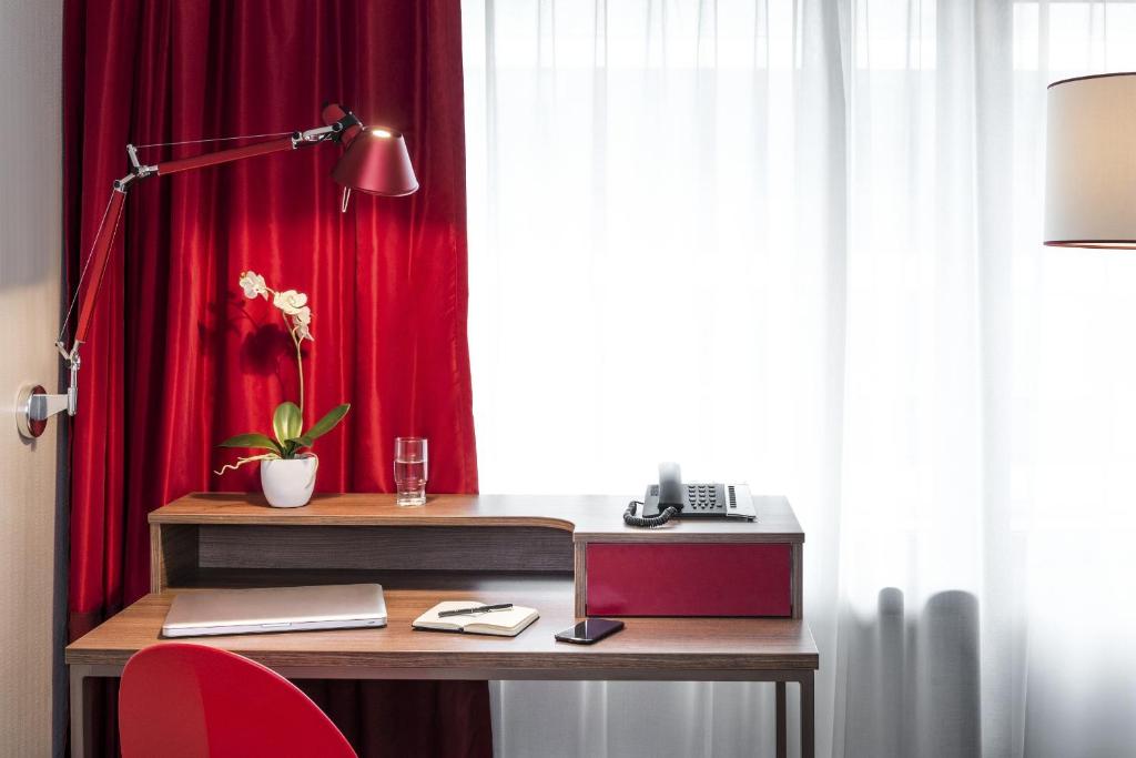 - un bureau avec une lampe et un rideau rouge dans l'établissement Aparthotel Adagio Paris Bercy Village, à Paris