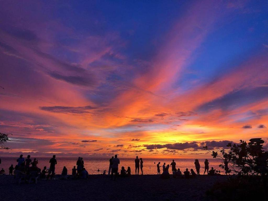 a group of people standing on a beach at sunset at Playa del Ritmo Beach Hostel & Bar - Adults Only in Santa Marta