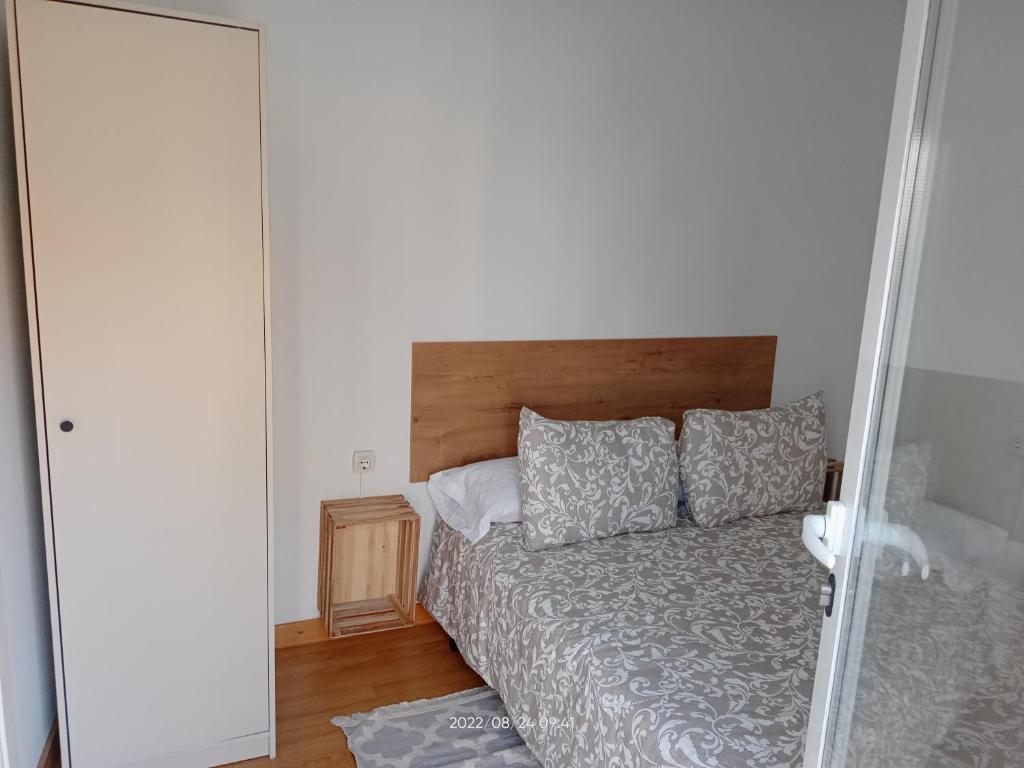 a bedroom with a bed with a wooden headboard at A casiña de Vilaxoan in Vilagarcia de Arousa