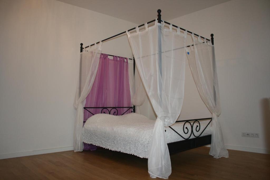 プラハにあるApartment Marilynのベッドルーム(ピンクのカーテン付きの天蓋付きベッド付)