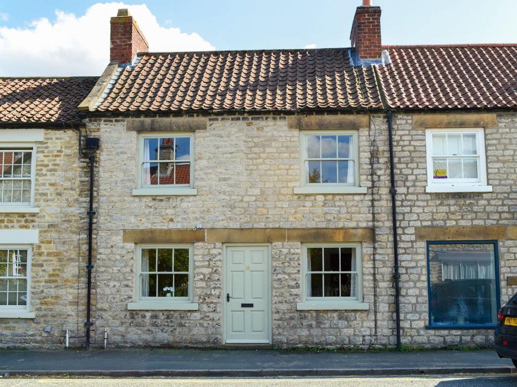 an old brick house with a white door at Bondgate in Helmsley