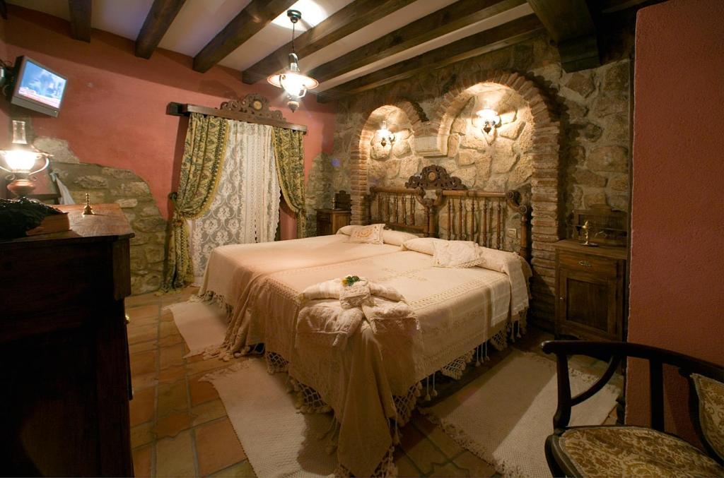 1 dormitorio con 1 cama grande en una pared de piedra en Casa Rural Margarita II, en Montánchez