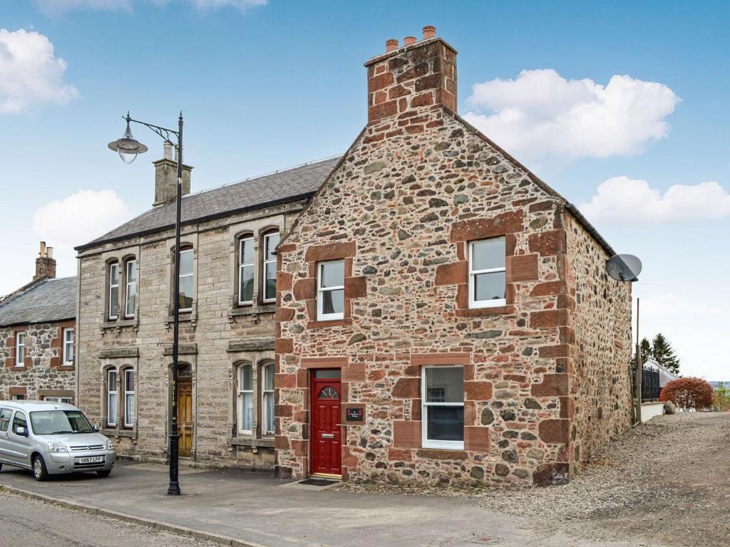 un antiguo edificio de piedra con una puerta roja en Carse View Cottage, en Abernethy