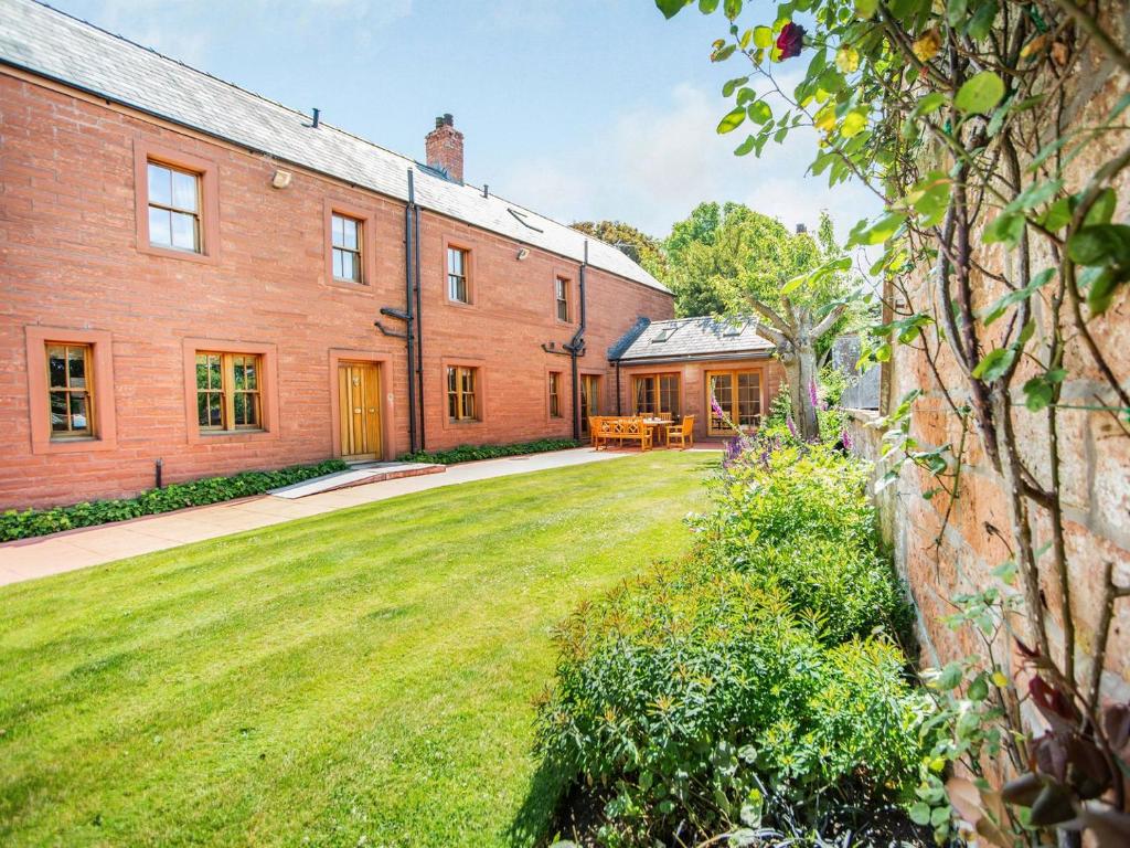 an exterior view of a large brick building with a yard at Garden Cottage - Uk34669 in Great Corby