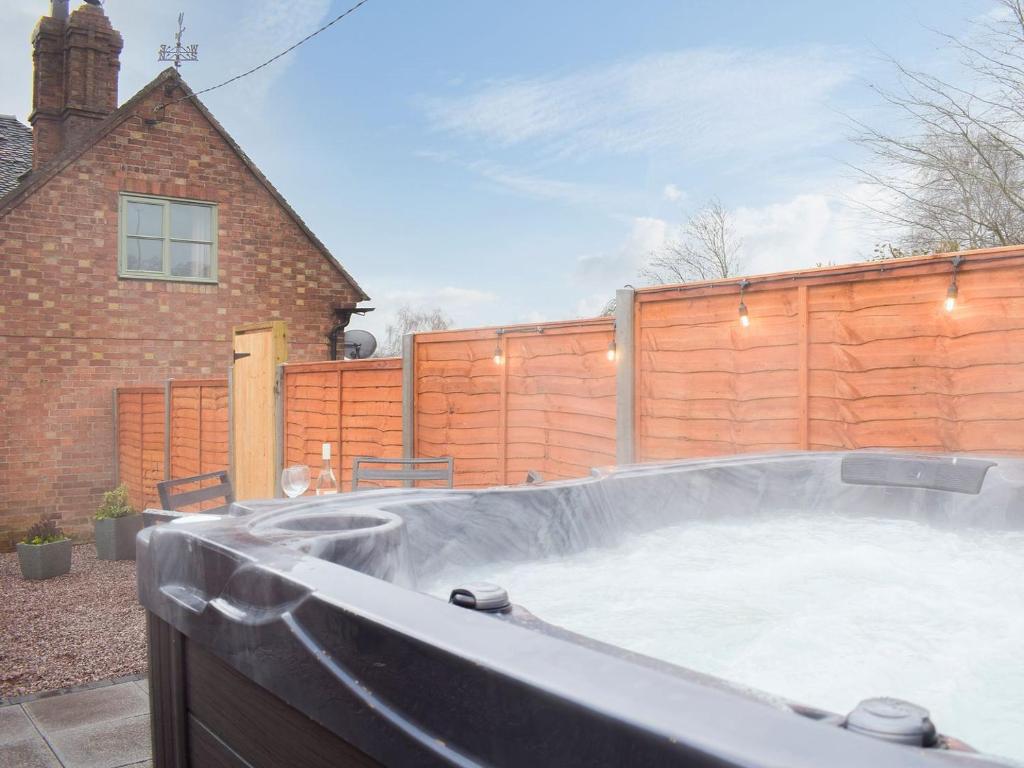 a large hot tub in a backyard with a fence at The Classroom in Bourton