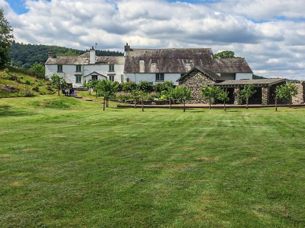 a large house on a hill with a large grass field at Sandfold Farm in Newby Bridge