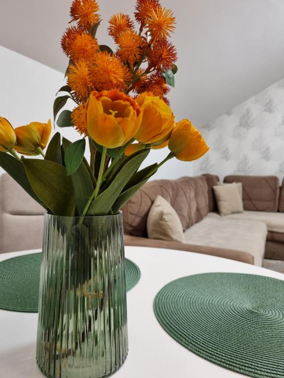 a vase of orange flowers sitting on a table at AS Delux Apartmani in Soko Banja
