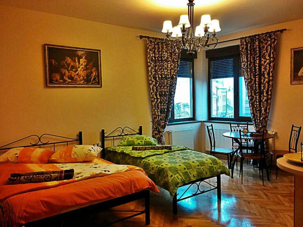 クルジュ・ナポカにあるMozart Apartmentsのベッドルーム1室(ベッド2台付)、ダイニングルーム(テーブル付)