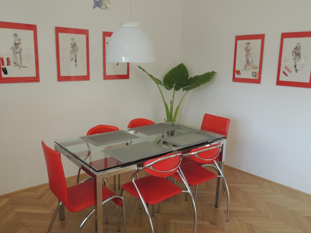 een eetkamer met een glazen tafel en rode stoelen bij Your Ljubljana Home in Ljubljana