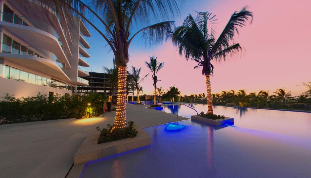 una piscina con palmeras y un edificio en Cartagena, gran experiencia frente al mar a 20 minutos del centro histórico y 13 minutos del aeropuerto, en Cartagena de Indias