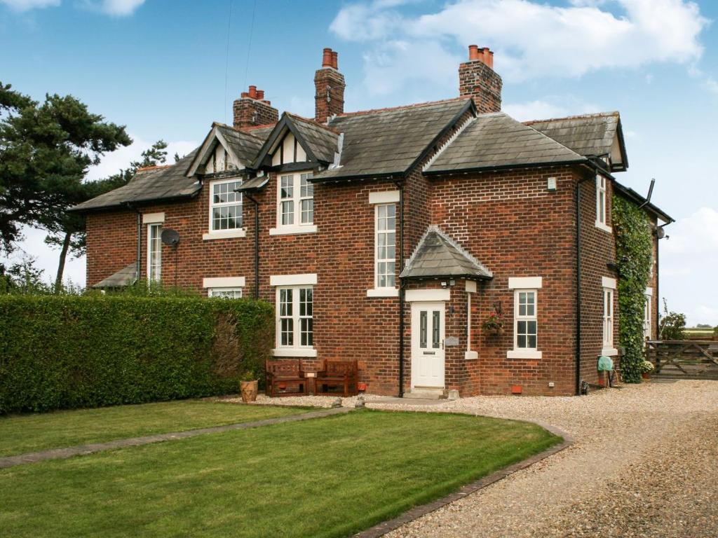 a large brick house with a lawn in front of it at Saswick Cottage in Elswick