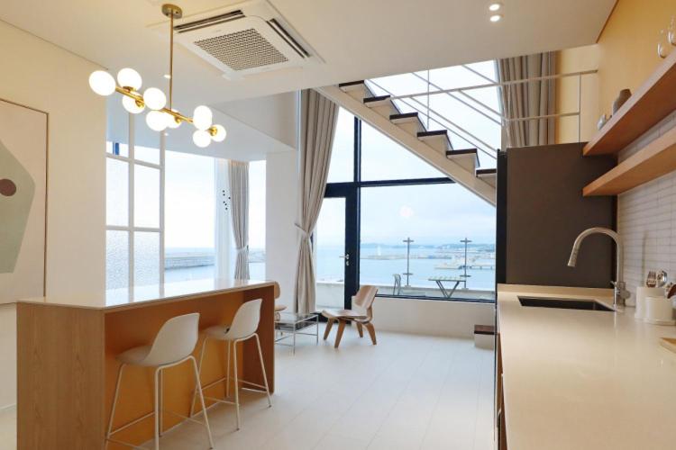 a kitchen with a bar with chairs and a large window at Bau Haus in Sokcho