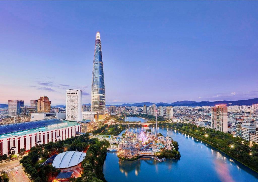 una città con un fiume e un edificio alto di Lotte Hotel World a Seul