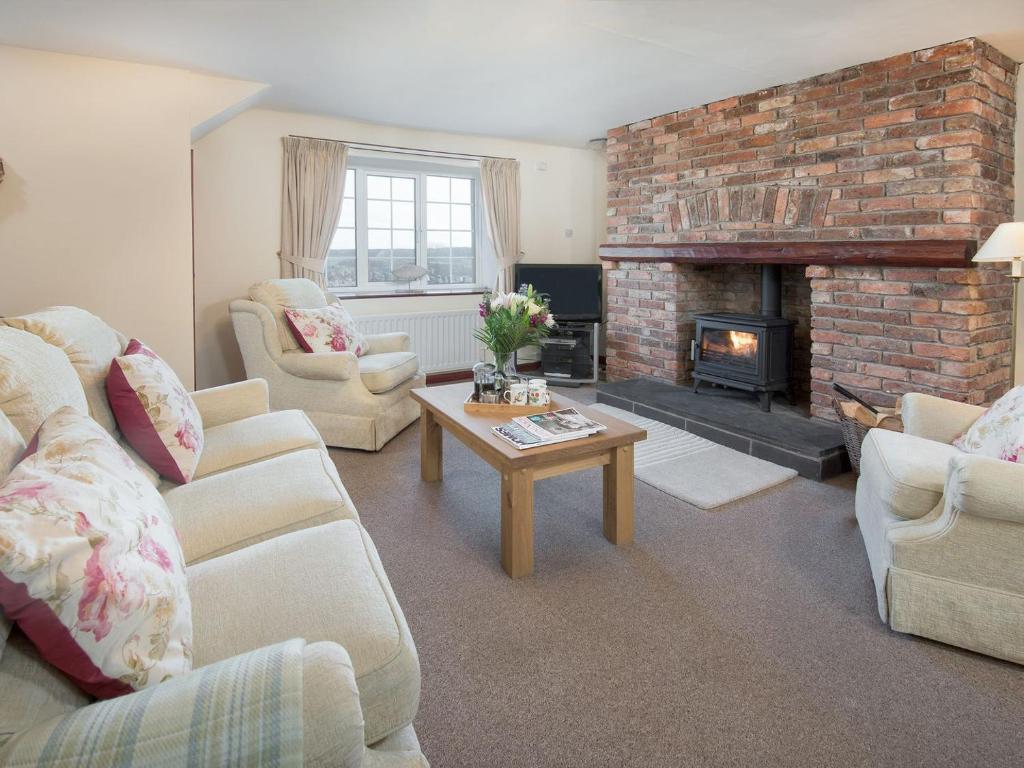 a living room with couches and a brick fireplace at Dunstanburgh View in Craster