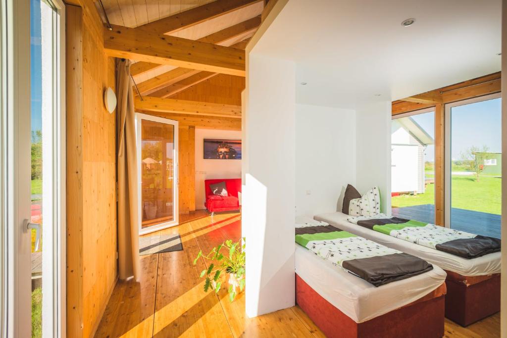 two beds in a room with wooden floors and windows at Ferienhaus Leipzig am Schladitzer See in Rackwitz