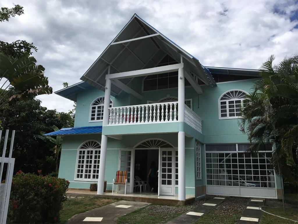 een blauw huis met een grote veranda bij GRANJA CAMPESTRE EN CONDOMINIO EL GUAMO-TOLIMA in Guamo