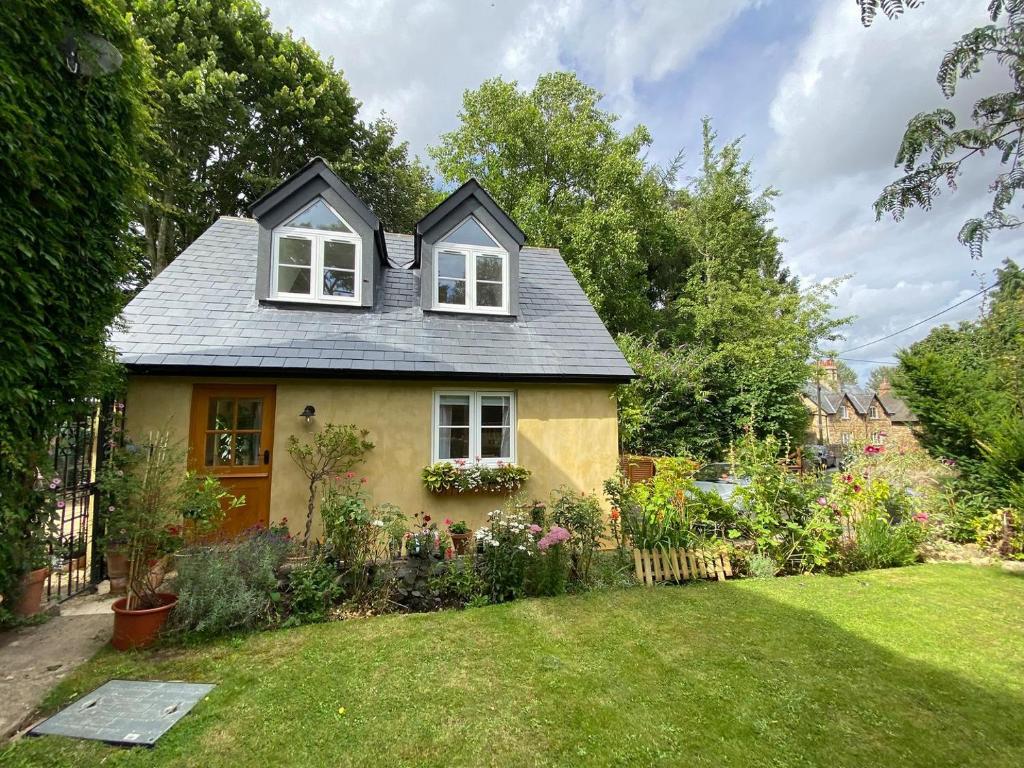 a yellow house with two windows and a yard at Candlewick Cottage in Steeple Aston