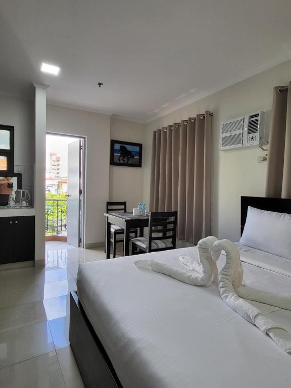 a bedroom with two beds and a table with a kitchen at Rooms R Us - Evangelista in Manila