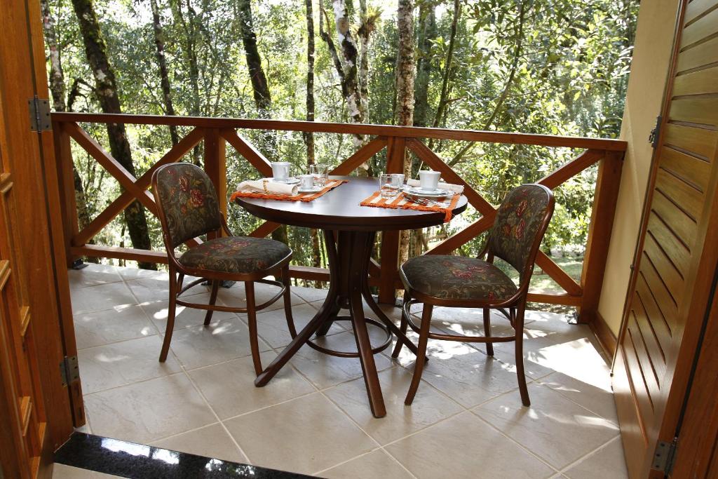 a table and chairs on a screened in porch at Pousada Chalé da Floresta in Monte Verde