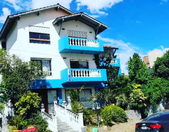 una casa blanca y azul con un coche aparcado delante de ella en Edificio Maracuja - Departamentos en Villa Gesell