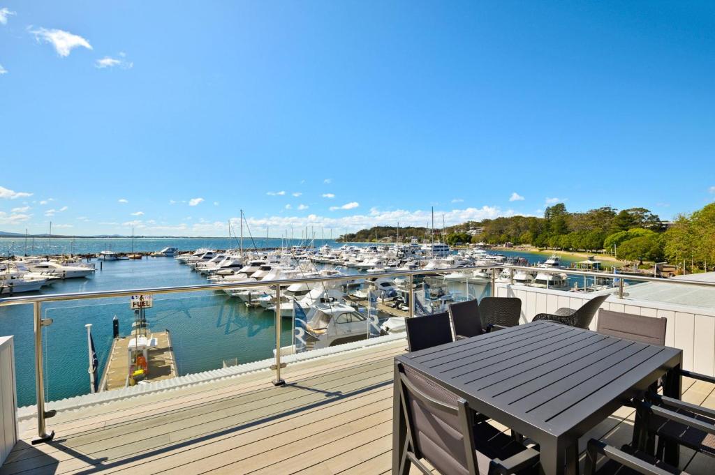 a balcony with a table and a marina with boats at Crows Nest 6 Teramby Road D Albora Marina in Nelson Bay