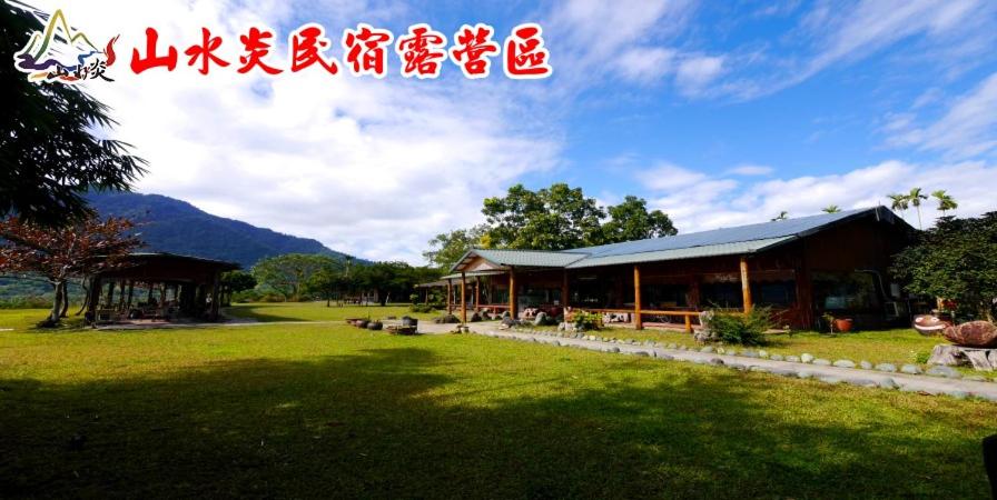 a building in a field with a grass yard at Shan Shui Yan Homestay in Liugui