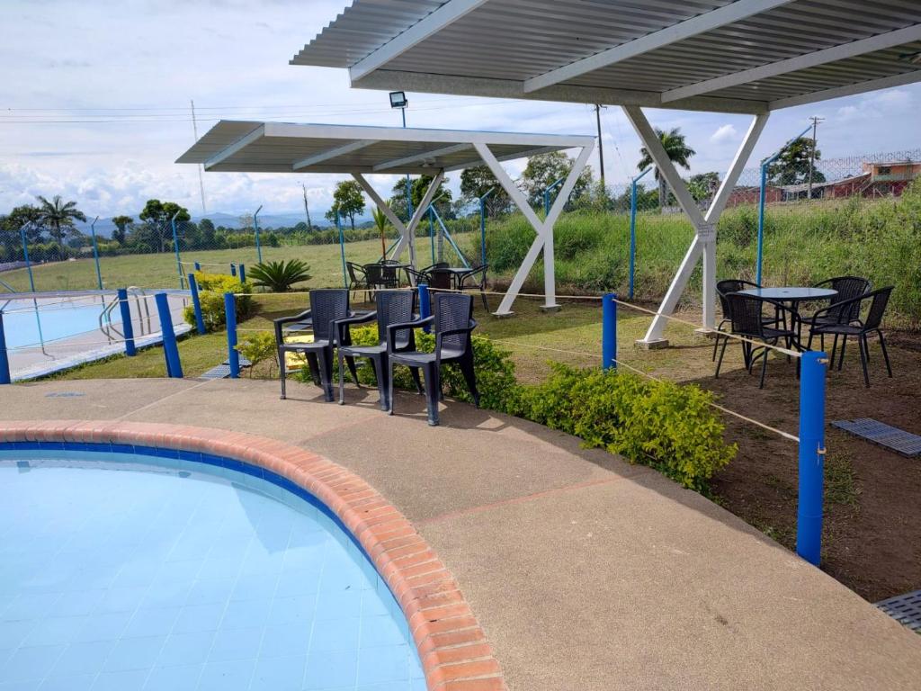 a swimming pool with chairs and a table and umbrellas at hospedaje del cafe in Montenegro