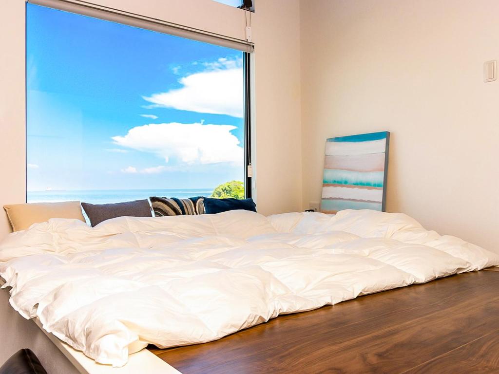 明石市にあるT.Squareの大きな窓付きの客室で、白い大型ベッド1台が備わります。