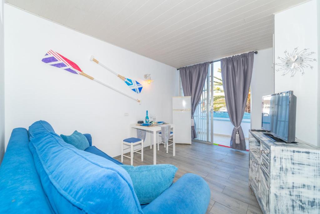 een woonkamer met een blauwe bank en een televisie bij Beach House Tenerife in Costa Del Silencio