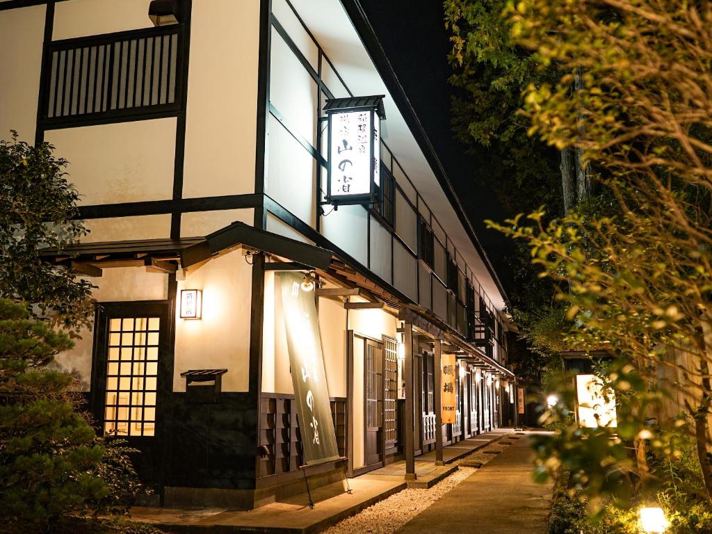 un bâtiment avec une horloge sur son côté la nuit dans l'établissement Hakone Onsen Yuyado Yamanoshou, à Hakone