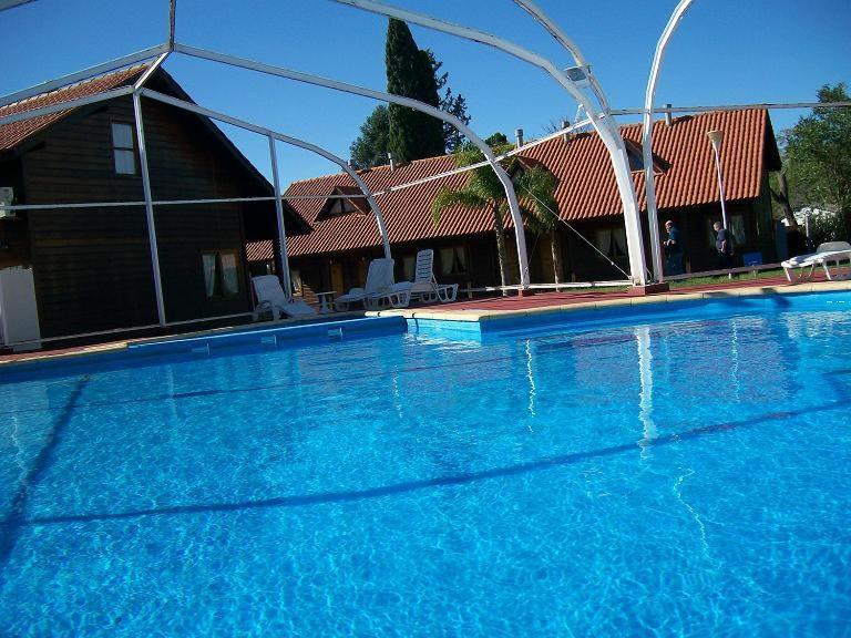 a large blue swimming pool in front of a house at Hotel Termal Dayman in Termas del Daymán