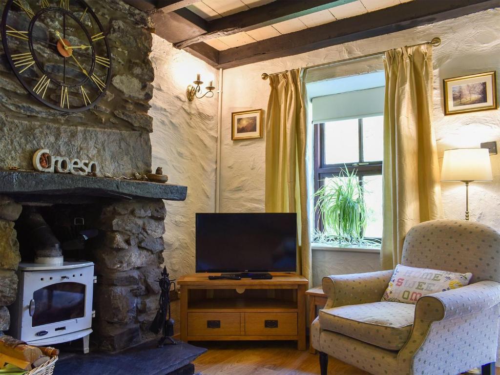 a living room with a tv and a stone fireplace at Uk34351 - Squirrel Cottage in Betws-y-coed