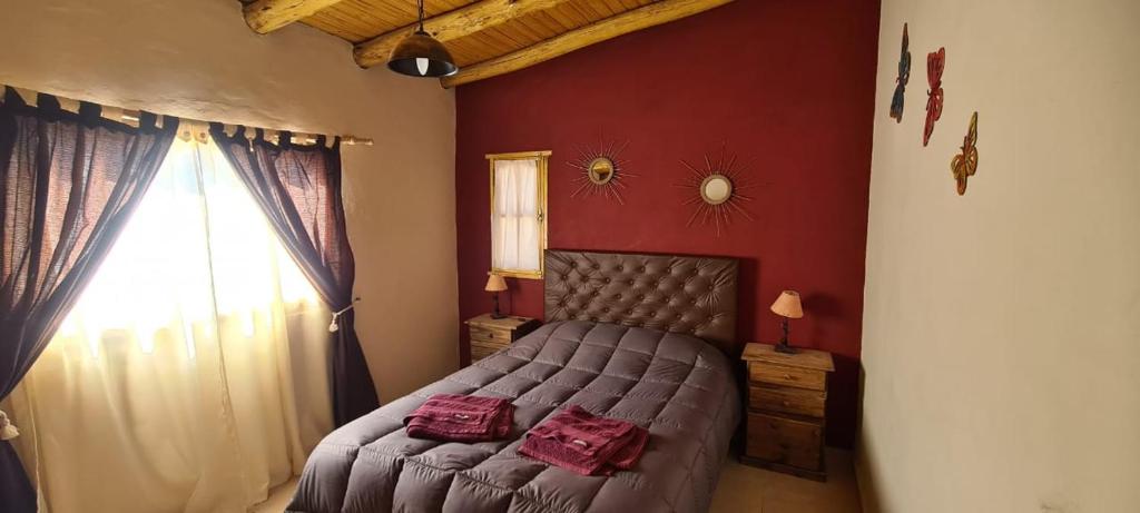 a bedroom with a bed with red walls and a window at La Comarca in Uspallata