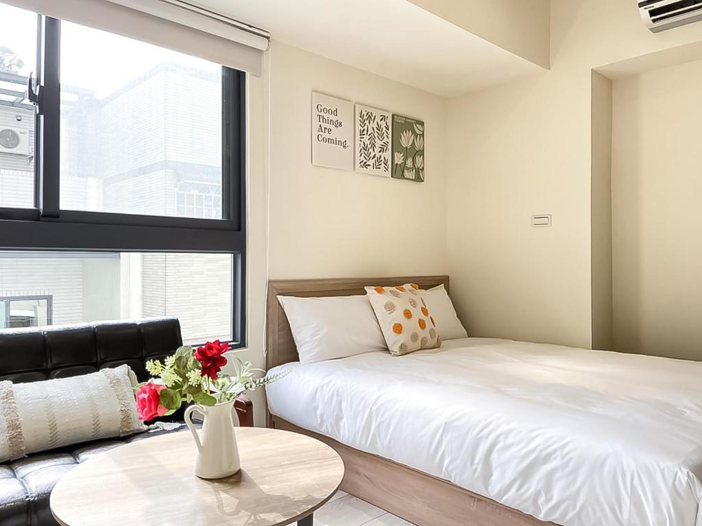 1 dormitorio con cama, mesa y sofá en 旅行家 Affetto Hostel en Taichung