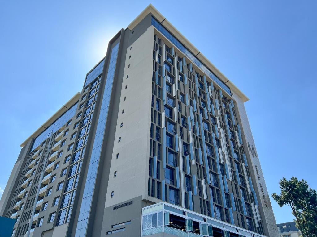 un edificio alto con un cielo azul en el fondo en CGRSA Apartments Sandton, en Johannesburgo