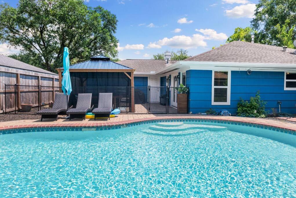 a swimming pool in front of a blue house at Stunning Pool and Chefs Kitchen NRG MedCenter in Houston