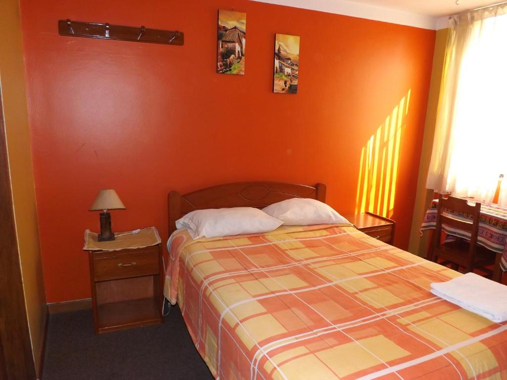 1 dormitorio con 1 cama con pared de color naranja en El Álamo, en Arequipa