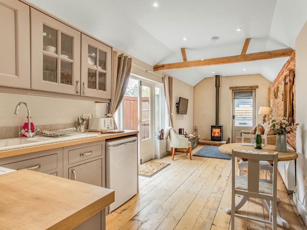 a kitchen with white cabinets and a table and a fireplace at Barwick Lodge in Bawdeswell