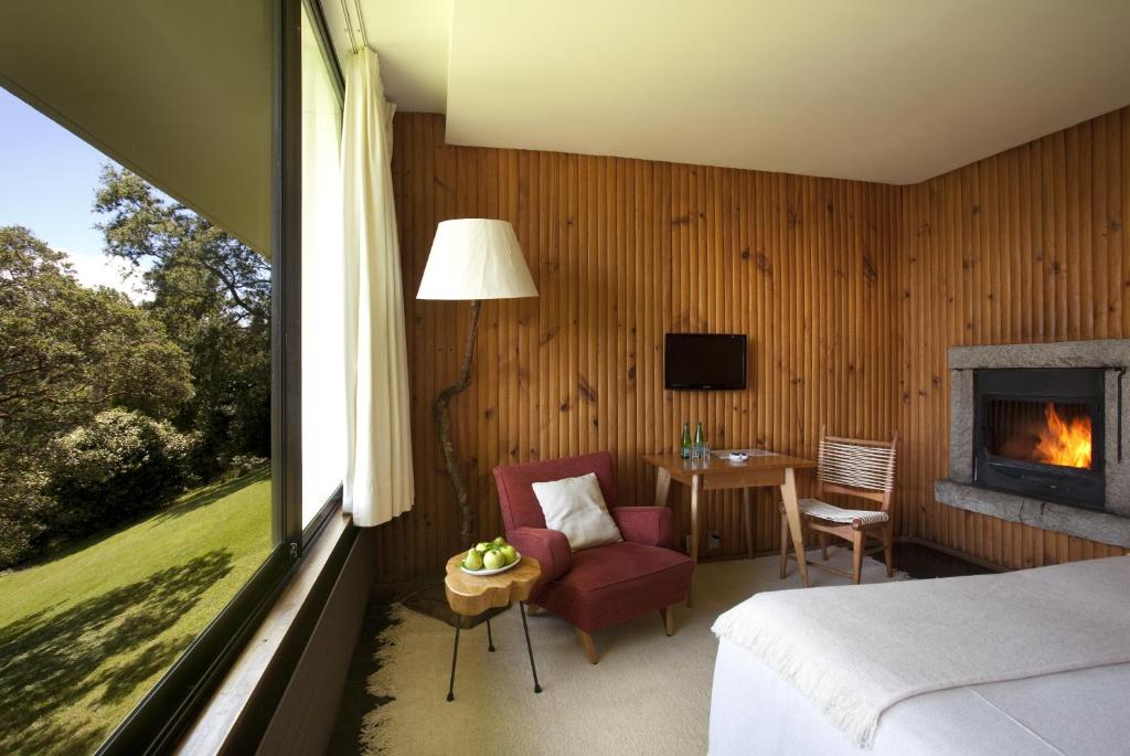 um quarto com uma cama, uma lareira e uma mesa em Hotel Antumalal em Pucón