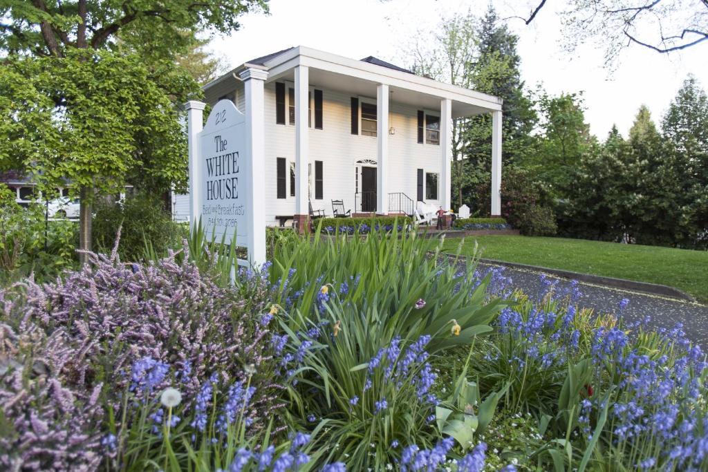 メドフォードにあるThe White House Bed and Breakfastの紫の花々が咲く白い家の前の庭