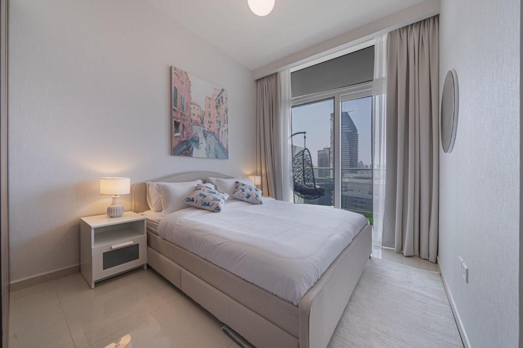 a white bedroom with a bed and a large window at Alluring 1 BD Apartment in Business Bay with Burj Khalifa view in Dubai