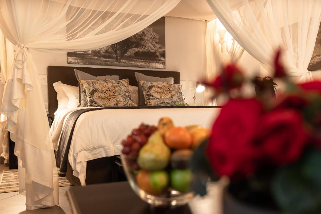 a bedroom with a bed with a bowl of fruit on a table at Kruger Eden Lodge in Marloth Park