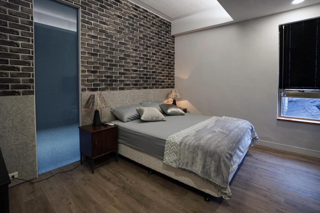 a bedroom with a bed and a brick wall at Mudan Gathering Homestay in Shuangxi