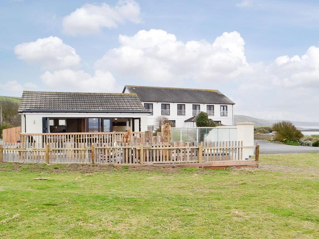 a house with a wooden fence in front of a yard at Plas Bach in Llanon