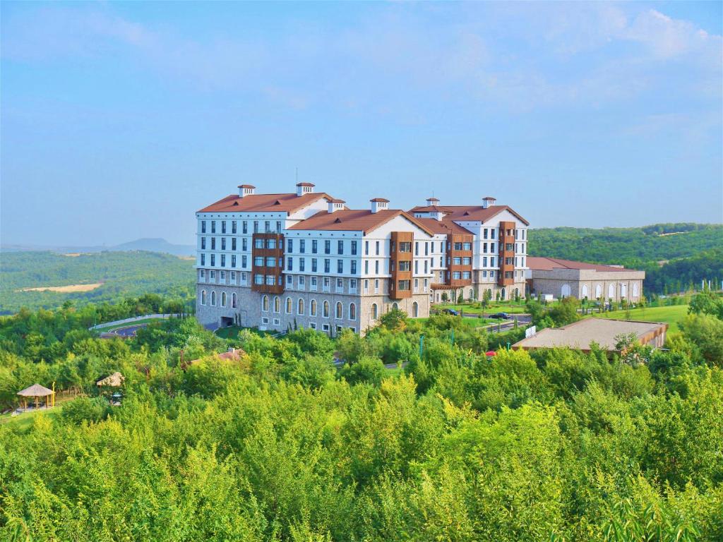 a large building on top of a hill with trees at Basqal Resort & SPA in Basqal