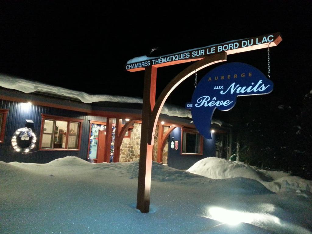 a street sign in the snow in front of a house at Auberge Aux Nuits de Rêve in Sainte-Agathe-des-Monts