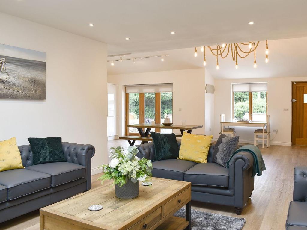 a living room with two couches and a table at Redstones Cottage in Greasby