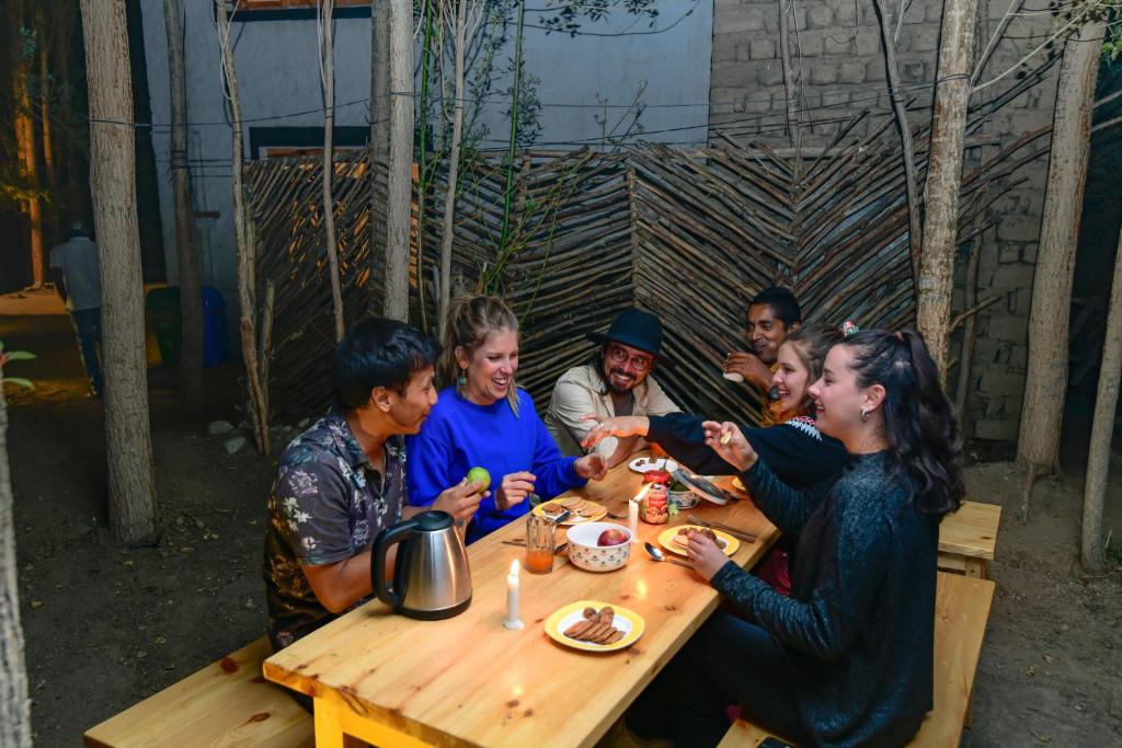 Raybo Hostel في ليه: مجموعة من الناس يجلسون على طاولة يأكلون الطعام